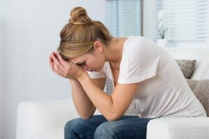 Donna con mani sul viso e gomiti sulle ginocchia, preoccupata