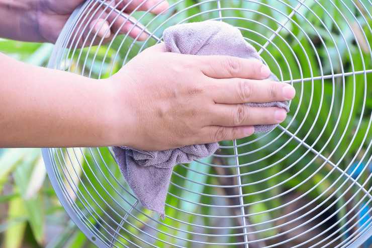 Persona pulisce la griglia del ventilatore