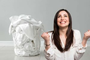 Cesta con bucato bianco, donna felice esulta