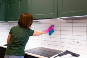 Donna pulisce piastrelle della cucina con panno in microfibra