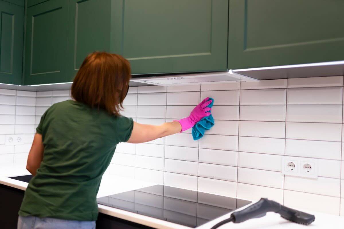 Donna pulisce piastrelle della cucina con panno in microfibra