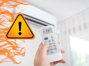 sfondo condizionatore e mano con telecomando e fuoco con simbolo pericolo