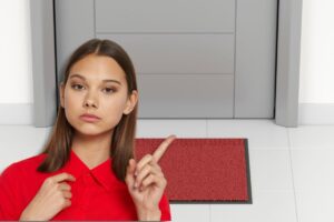 Donna seria indica, uscio di casa con tappeto rosso