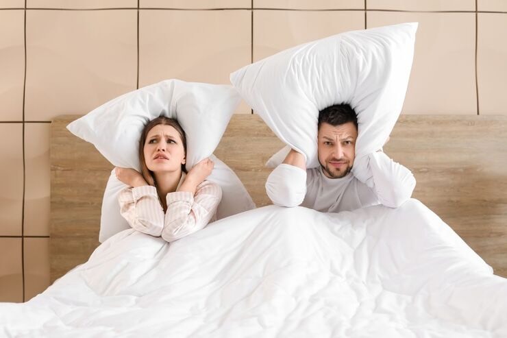 Coppia con cuscino sulle orecchie nel letto