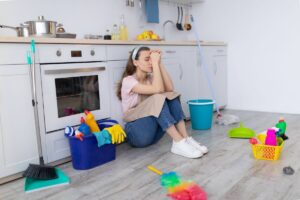 Ragazza seduta davanti la cucina con attrezzi e strumenti per fare le pulizie