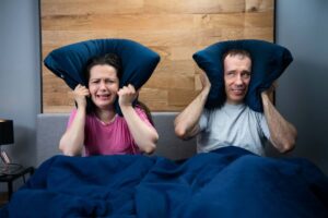 Marito e moglie si tappano orecchie nel letto con i cuscini