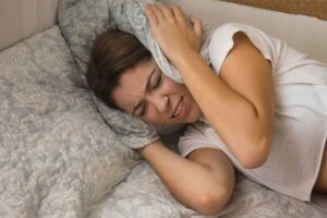 Donna si tappa orecchie con cuscino nel letto