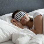 donna che dorme nel letto con mascherina su occhi