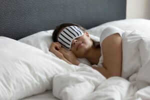 donna che dorme nel letto con mascherina su occhi