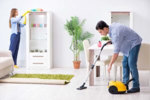 donna che spolvera e uomo con aspirapolvere