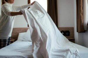 Una donna che sta cambiando le lenzuola del letto