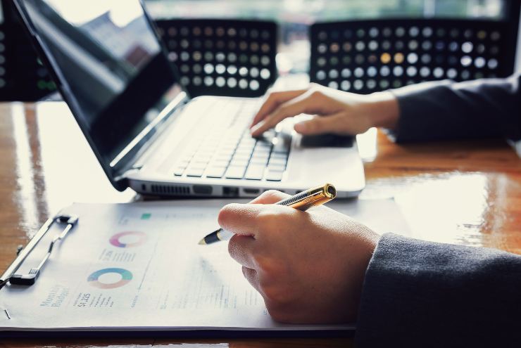 Persona utilizza un computer con dei documenti davanti