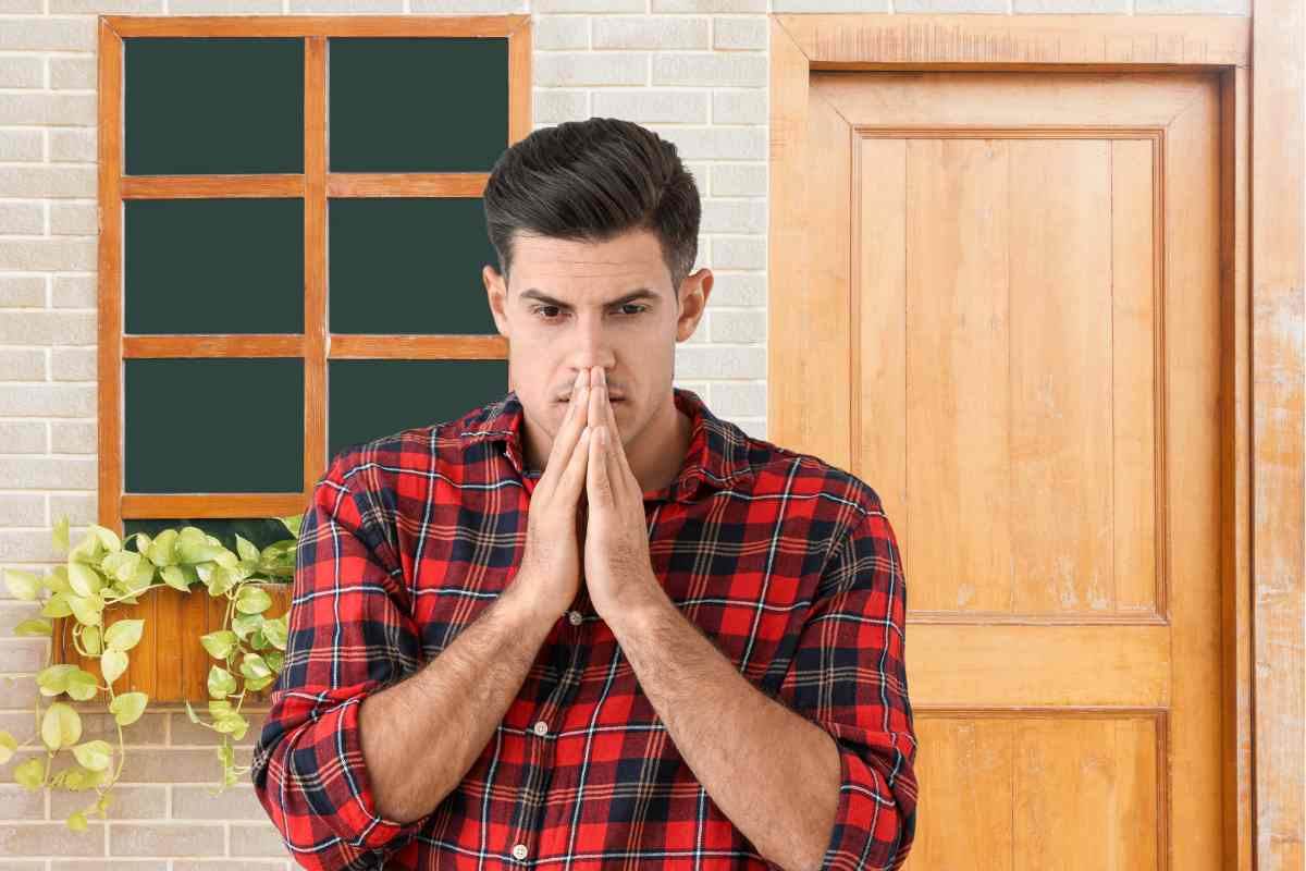 Uomo preoccupato con casa sullo sfondo