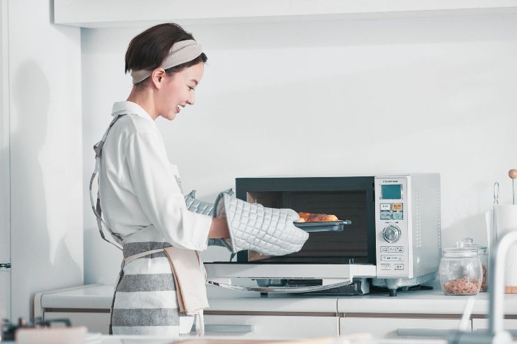 Ragazza cuoce con un piccolo forno multiuso 