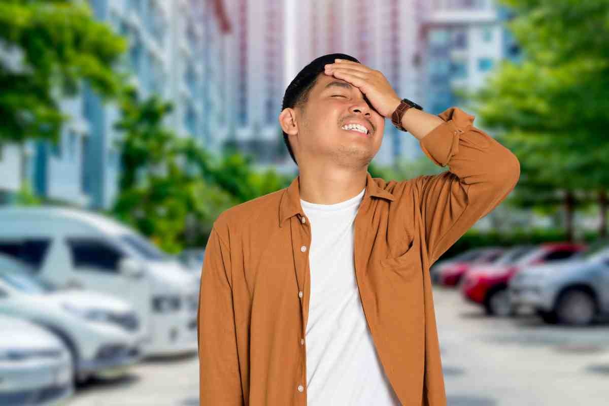 Uomo con mano sulla fronte e parcheggio