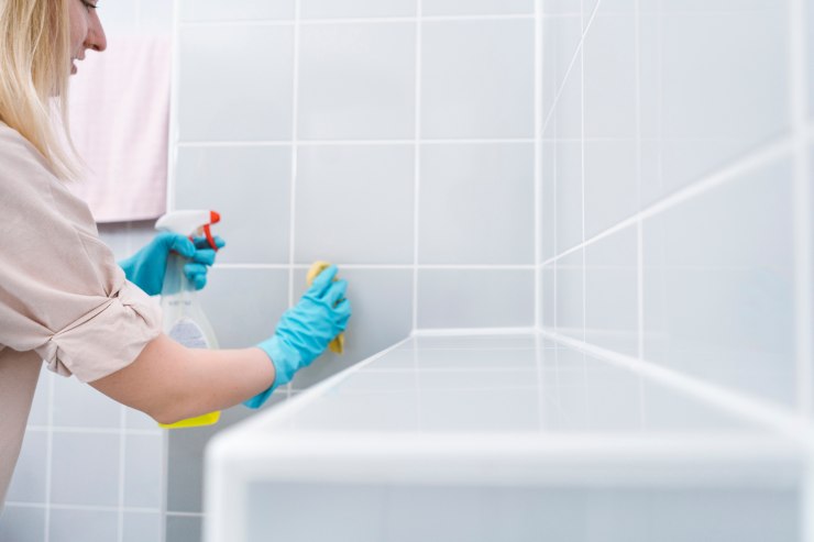 Una donna che sta lavando le piastrelle del bagno 