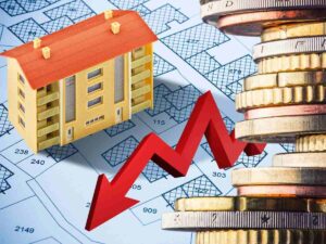 sfondo casa in miniatura e documenti catasto e monete euro con freccia in giù