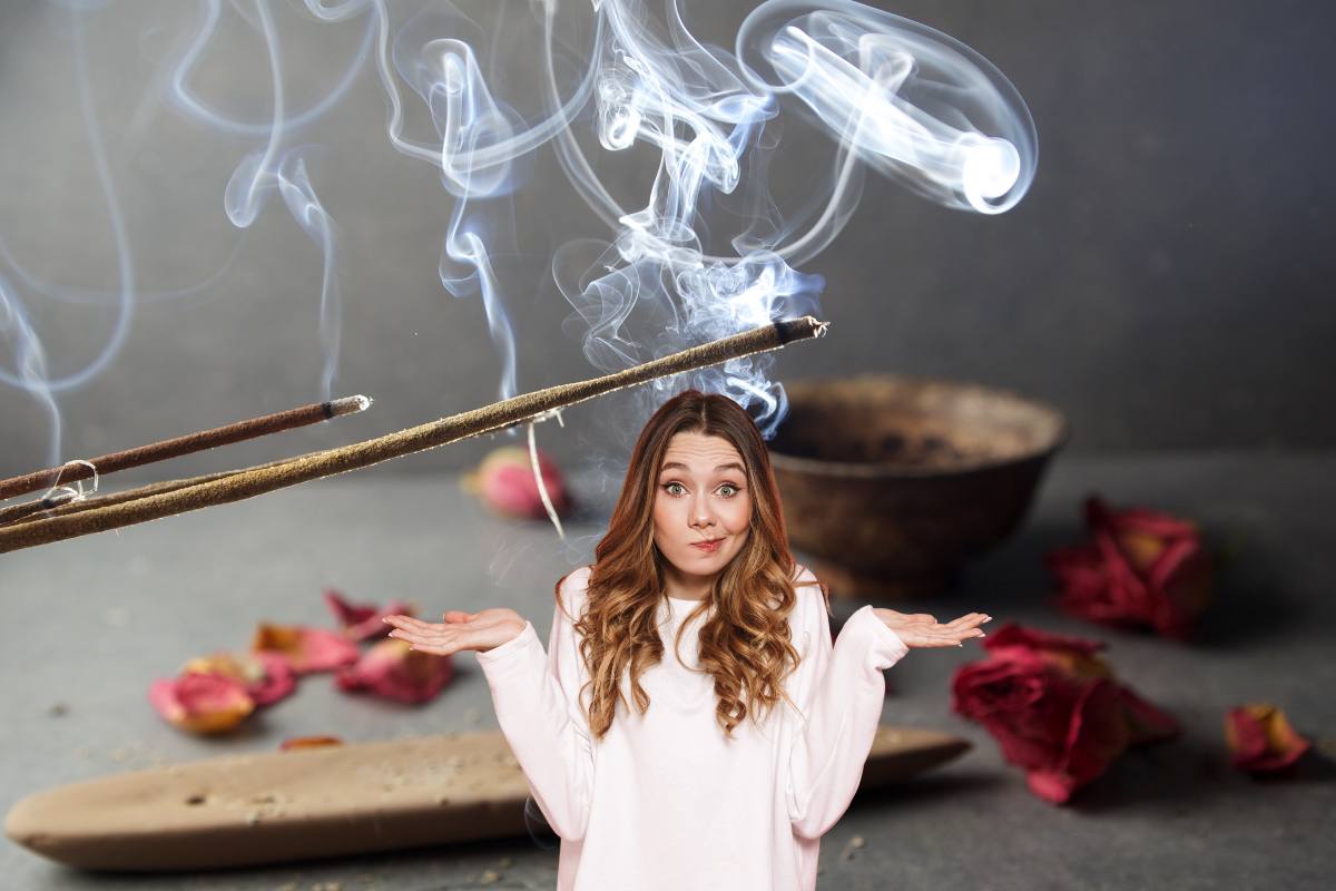 Una donna dubbiosa in primo piano con dell'incenso sullo sfondo