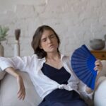 Donna sul divano accaldata sventola ventaglio