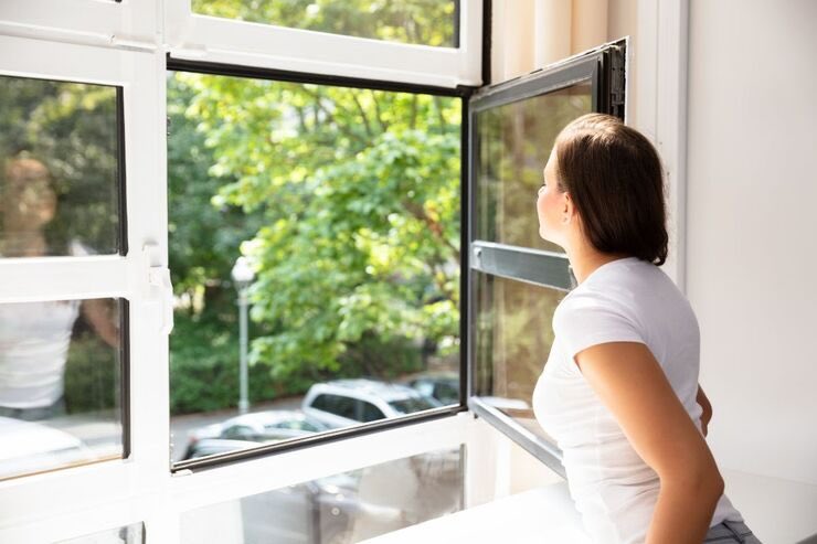 Donna respira aria che entra dalla finestra aperta 