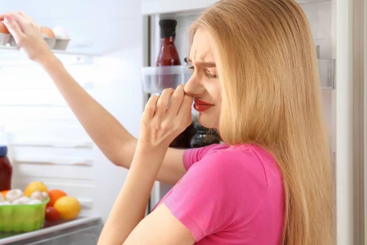 Donna con naso tappato mentre apre frigorifero