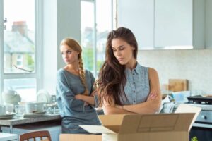 Due donne in casa, una davanti scatoloni, aria pesante fra loro
