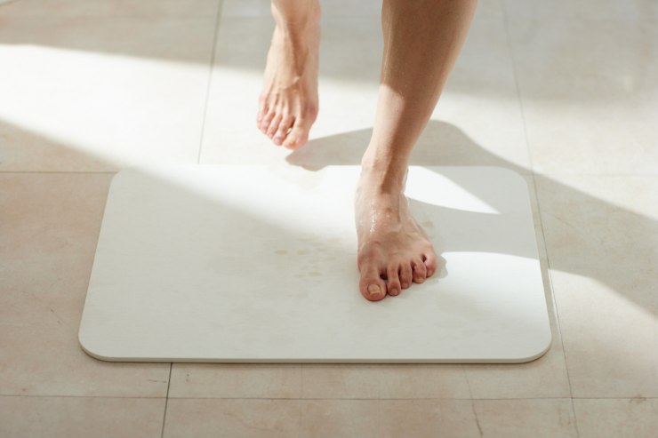 un tappeto da bagno in diatomite con una persona che ci sale sopra