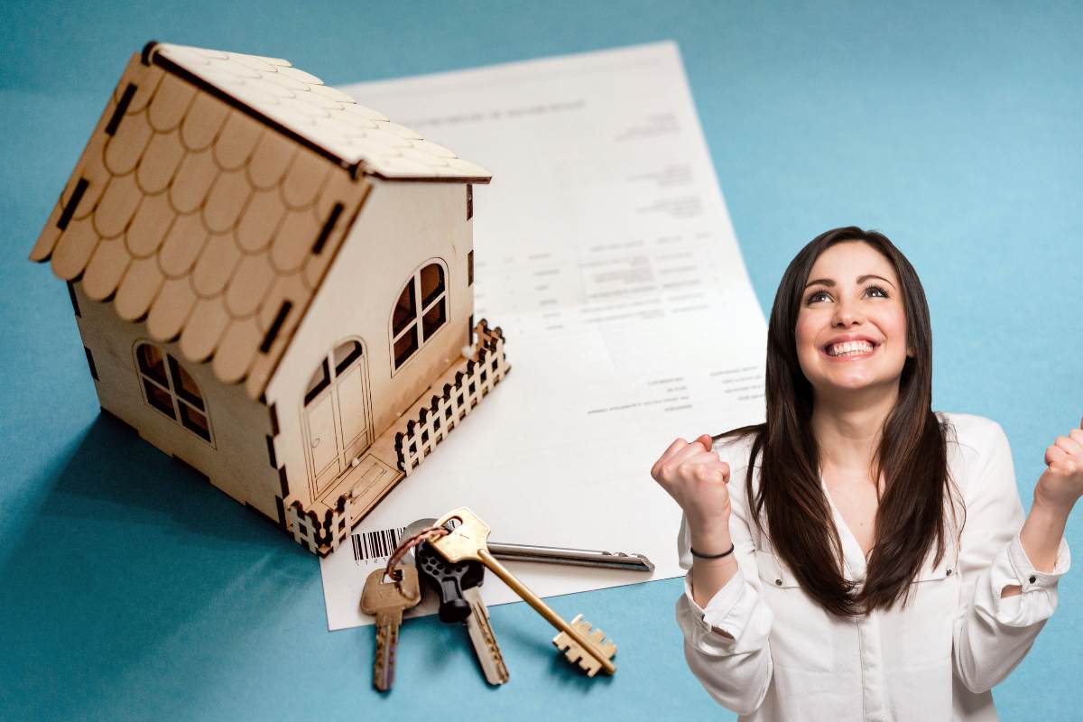 Una miniatura in legno di una casa con un documento e delle chiavi ed una donna sulla destra che esulta