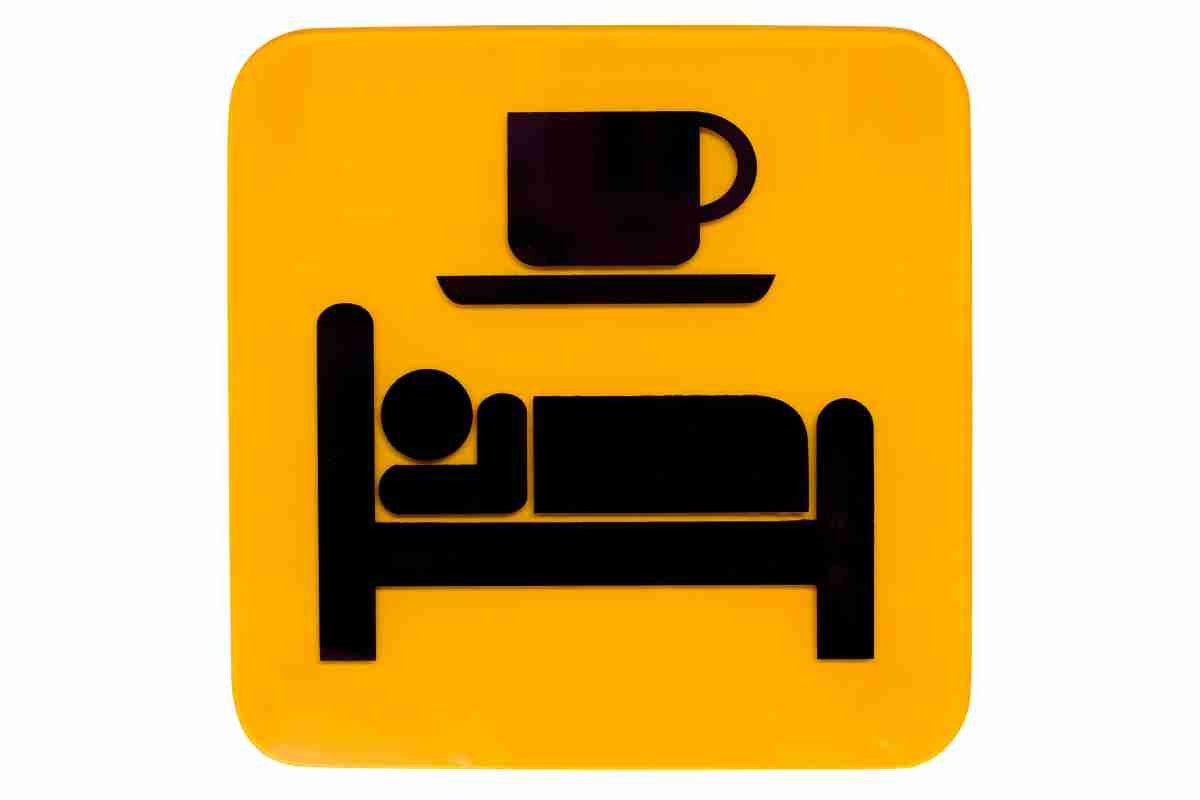 cartello con tazza e letto con persona che dorme