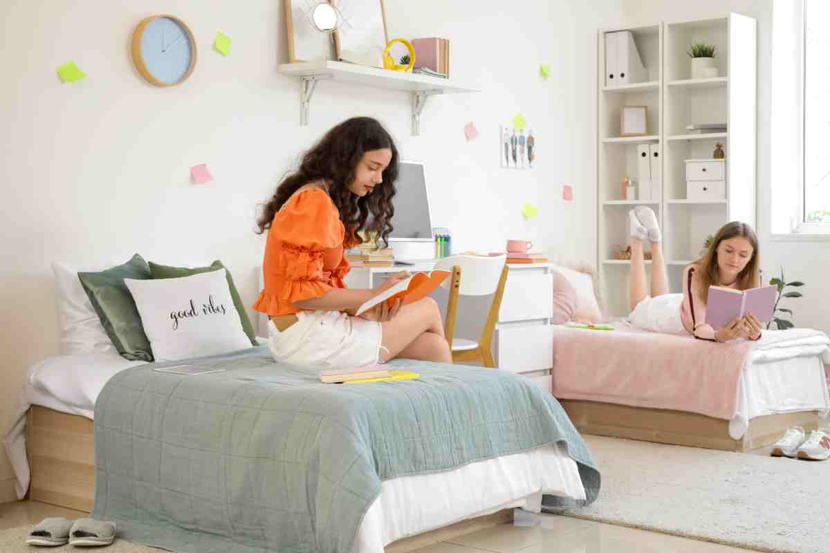 due ragazze studiano sul letto di una stanza condivisa