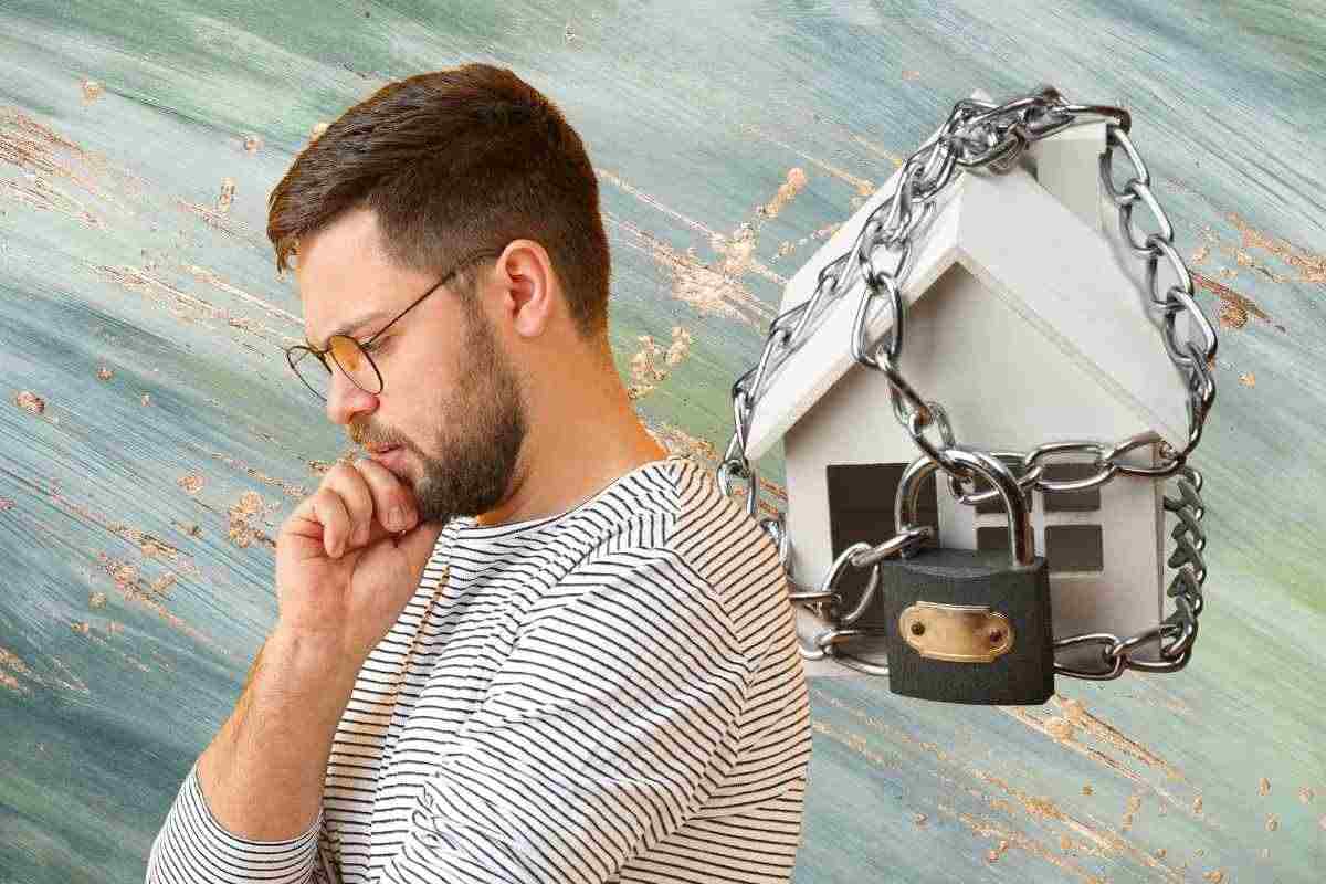 Uomo pensieroso e casa con il lucchetto
