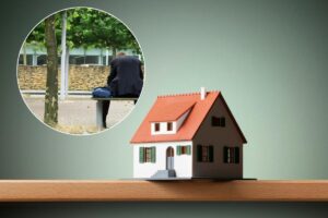 casa in miniatura e uomo sulla panchina