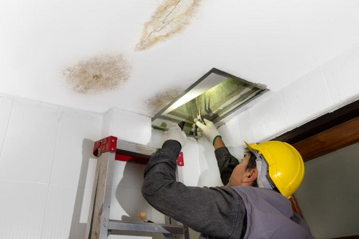 Una persona che sta riparando il soffitto da delle perdite