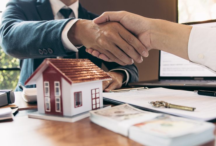 casa in miniatura e stretta di mano
