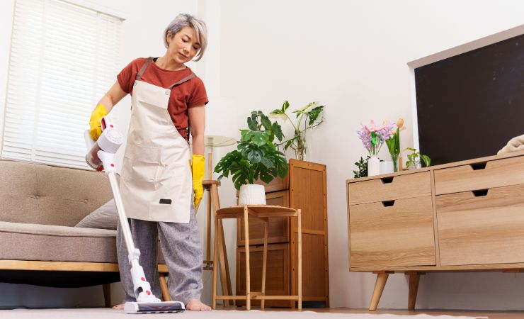 donna che passa l'aspirapolvere in casa 