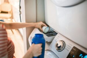 Una persona che mette il detersivo nella lavatrice