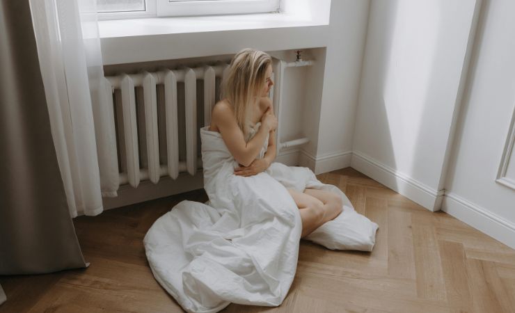 donna con trapunta accanto al termosifone