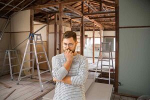 dei lavori di ristrutturazione in casa ed un uomo in primo piano preoccupato
