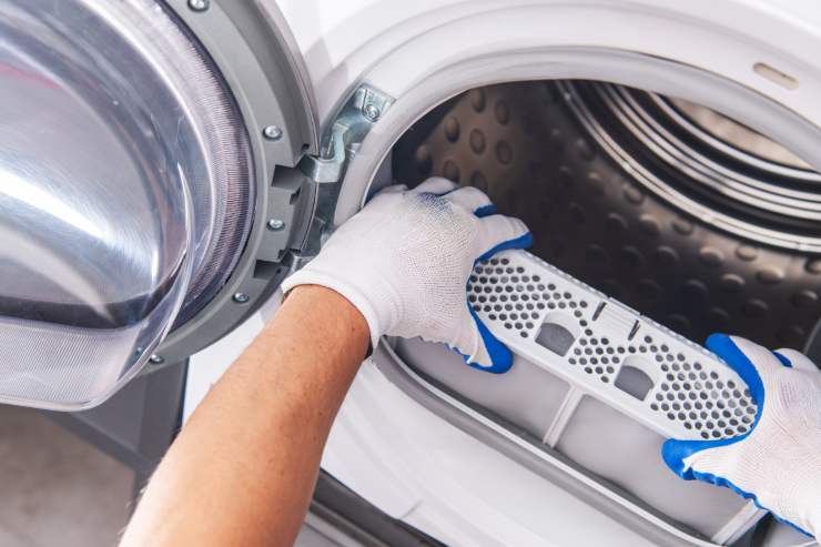 Un signore che sta pulendo la lavatrice