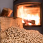 Una stufa a pellet sullo sfondo con in primo piano il pellet