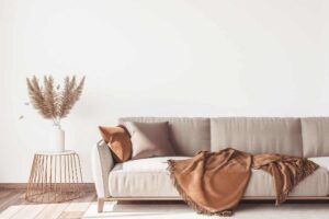 divano beige con copertina color bronzo e tavolinetto di lato