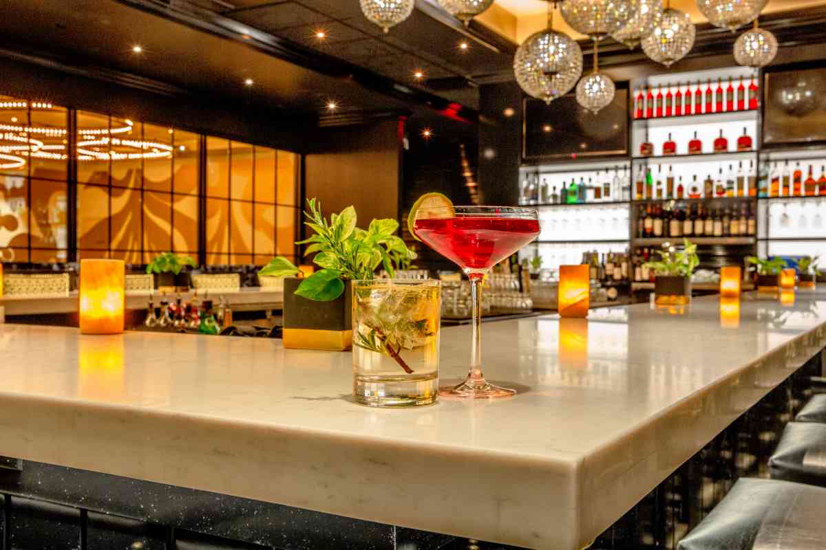 bancone di un bar con cocktail e vetrine illuminate