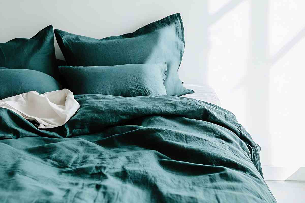 un letto disfatto con lenzuola color ottanio