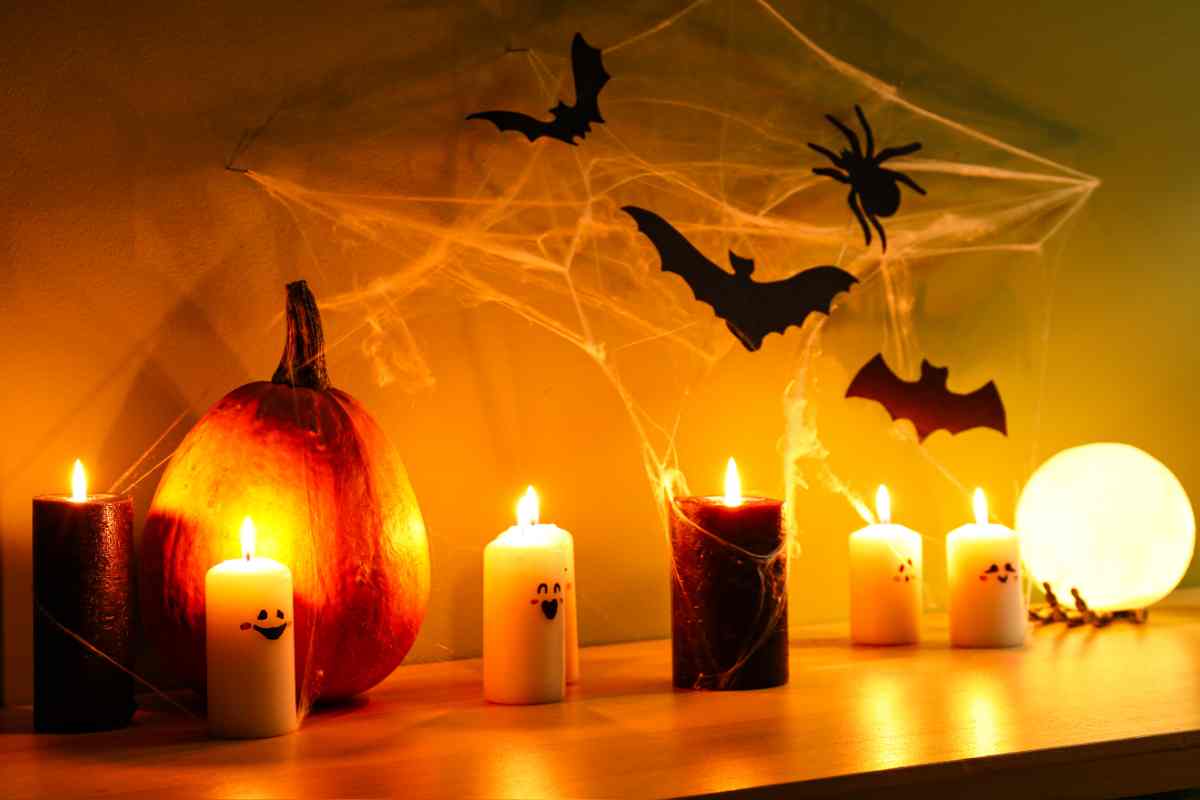 una mensola con diversti tipi di candela spaventosa per halloween e pipistrelli con ragnatele