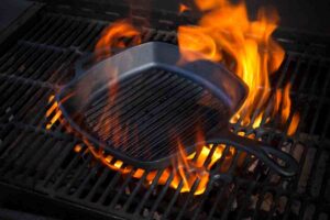una bistecchiera in ghisa sopra alla griglia del barbecue