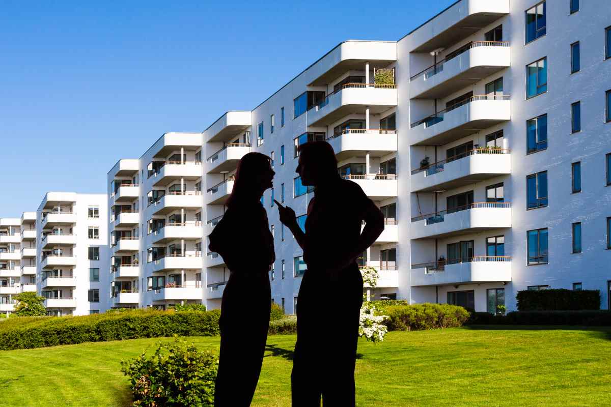 Un grande condominio in sfondo e in primo piano due sagome che litigano