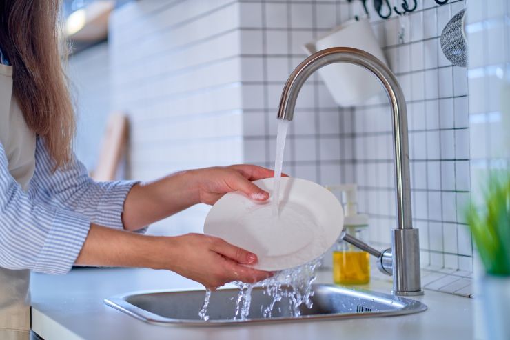 Una persona che lava i piatti nel lavandino