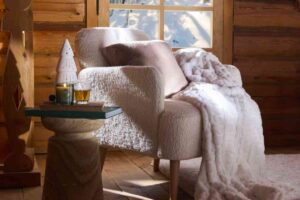 poltrona con coperta su tappeto e vicino un tavolino in un rifugio boreale