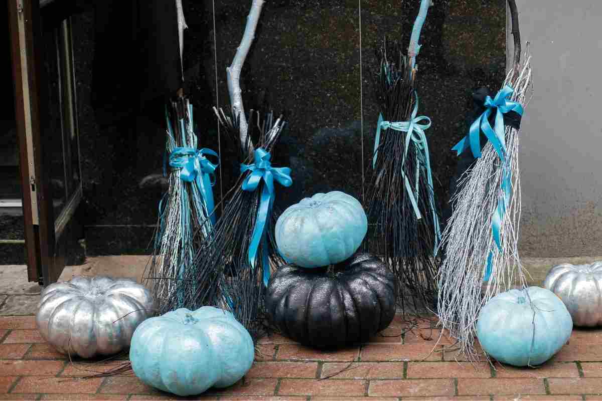 diverse scope da strega di Halloween di colori scuri vicino a zucche colorate