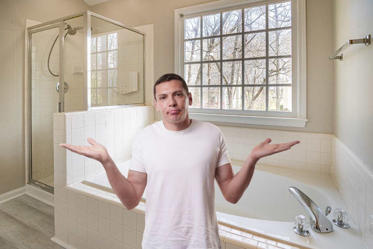 Un bagno con doccia e vasca ed un uomo indeciso in primo piano